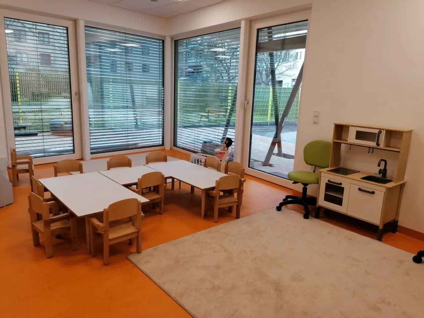Außengelände der Kita StarKids mit Wiese und Bäumen